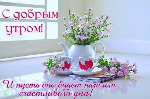 Открытка «С добрым утром!»: нежные фиолетовые цветы, чашки с сердцами и пожелание счастливого дня. Идеально для отправки близким для хорошего настроения! Открытка С добрым утром! И пусть оно будет началом счастливого дня! Красивая открытка с пожеланием доброго утра. На нежном светлом фоне изображен букет фиолетовых цветов в белом чайнике, две чашки с красными сердцами и уютная обстановка. Текст на русском языке гласит: 