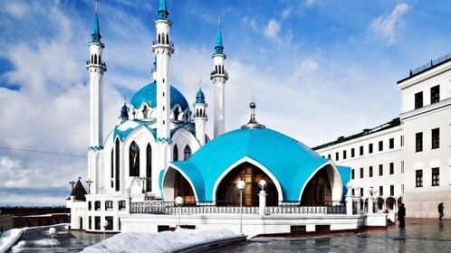 Мечеть Кул-Шариф в Казани: величественная архитектура с голубыми куполами и минаретами на фоне голубого неба. Символ Татарстана и красоты исламского зодчества. Открытка Мечеть кул шариф Величественная мечеть Кул-Шариф в Казани, запечатленная на фоне чистого голубого неба. На фотографии видна архитектурная красота белокаменного здания с ярко-голубыми куполами и высокими минаретами. Снежный ландшафт и современная городская застройка подчеркивают масштаб и духовную значимость мечети как одного из главных символов Татарстана