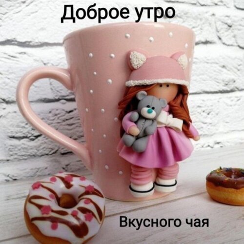 Доброе утро! Милая розовая кружка с девочкой и мишкой, аппетитные пончики и пожелание вкусного чая. Идеальная картинка для доброго утра и уюта. Открытка Доброе утро Вкусного чая Милое и уютное изображение розовой кружки с объемным декором в виде маленькой девочки с мишкой, предназначенное для пожелания доброго утра. На переднем плане расположены аппетитные пончики с глазурью. Композиция на светлом кирпичном фоне создает теплую, домашнюю атмосферу