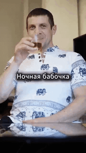 Смешной мем с надписью Ночная бабочка: мужчина пьет из бокала в рубашке со слонами. Популярная юмористическая GIF-анимация. Анимированная открытка Юмор Смешная GIF-анимация с мужчиной, который делает глоток из бокала, демонстрируя удовлетворение. На видео наложен текст на русском языке: 