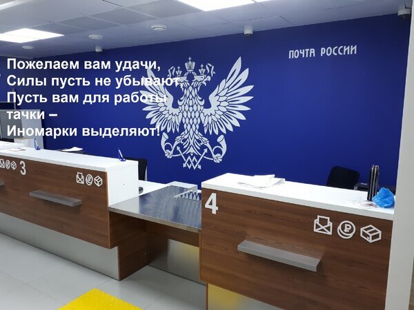 Интерьер отделения Почты России с логотипом и рабочими местами сотрудников. На фото наложен текст с пожеланиями удачи в работе. Открытка Пожелаем вам удачи, Силы пусть не убывают, Пусть вам для работы тачки – Иномарки выделяют! Изображение представляет собой интерьер современного отделения Почты России с брендированной синей стеной, на которой изображен крупный белый двуглавый орел. На переднем плане расположены рабочие места сотрудников — белые и деревянные стойки обслуживания с номерами окон (3 и 4). Поверх фотографии наложен текст на русском языке в стихотворной форме с пожеланиями удачи и сил в работе