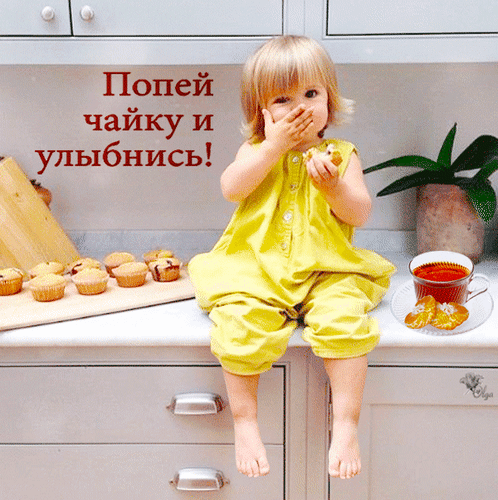 Маленькая девочка в желтом комбинезоне ест капкейк на уютной кухне. Надпись: «Попей чайку и улыбнись!». Теплое, позитивное семейное фото для лайфстайла. Анимированная открытка Попей чайку и улыбнись! На уютной светлой кухне маленькая девочка в ярко-желтом летнем комбинезоне сидит на столе и с аппетитом ест капкейк, прикрывая рот рукой. Рядом на столе разложены свежие кексы на деревянной доске, стоит чашка ароматного чая с дольками апельсина и стоит комнатное растение в горшке. На изображении наложен вдохновляющий текст на русском языке: 