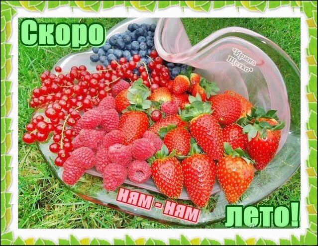 Аппетитная композиция из свежих ягод: клубники, малины, смородины и черники на сердцевидном блюде. Надпись: «Скоро ням-ням лето!» — идеальное летнее настроение. Открытка Скоро лето! Ням - ням! Яркая и сочная летняя композиция из свежих ягод, представленная на прозрачном блюде в форме сердца. На фото изображены спелые клубника, малина, красная смородина и черника, разложенные на зеленом фоне травы