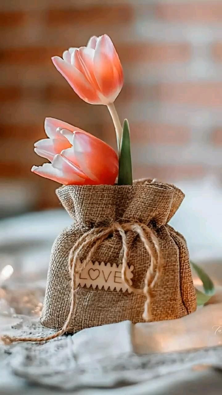Открытка люблю тебя. two tulips in a burlock bag on a table with the word love written on it