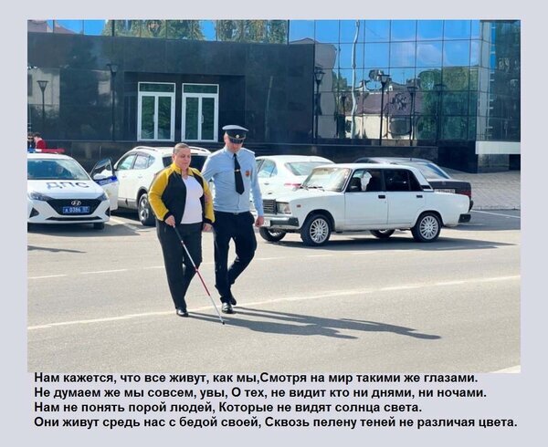 Женщина с тростью для слабовидящих идет рядом с полицейским на фоне автомобилей. Изображение о социальной поддержке и восприятии мира людьми с инвалидностью. Открытка Нам кажется, что все живут, как мы, Смотря на мир такими же глазами. Не думаем же мы совсем, увы, О т На фотографии запечатлена сцена на городской улице: женщина с нарушениями зрения, использующая белую трость, идет рядом с сотрудником полиции в форме. На заднем плане припаркованы автомобили, включая белый седан и полицейскую машину. Изображение сопровождается эмоциональным текстом на русском языке о восприятии мира людьми с ограниченными возможностями и важности эмпатии