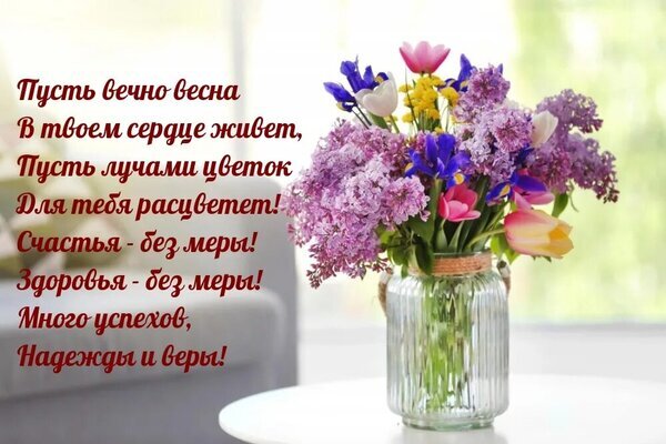 Красивая открытка с букетом весенних цветов (сирень, тюльпаны, ирисы) и душевным текстом с пожеланиями счастья, здоровья и вечной весны в сердце. Открытка Будьте счастливы Красивое поздравительное изображение с букетом весенних цветов в стеклянной вазе. На картинке изображены нежные сиреневые цветы, тюльпаны и ирисы, символизирующие весну и обновление. Слева расположен трогательный текст на русском языке с пожеланиями вечной весны в сердце, безмерного счастья, крепкого здоровья, успехов, надежды и веры